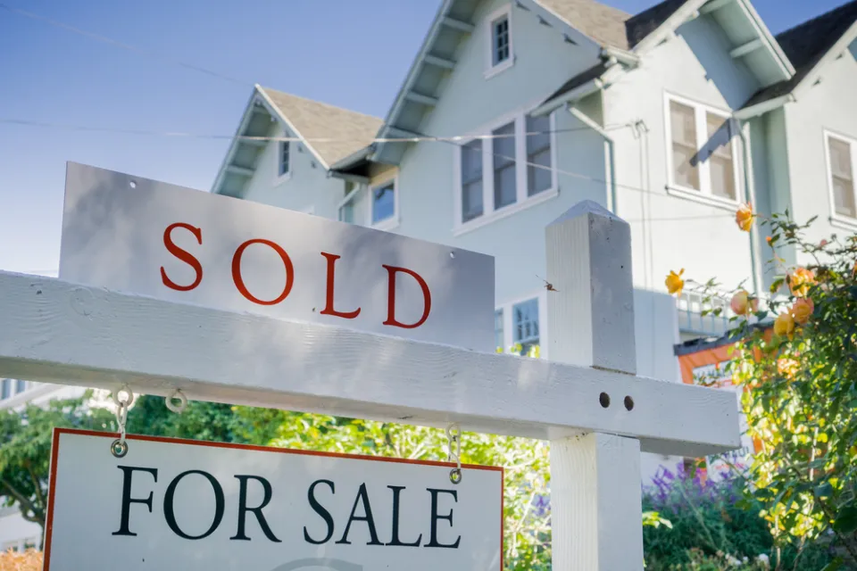 White house with For Sale and SOLD sign